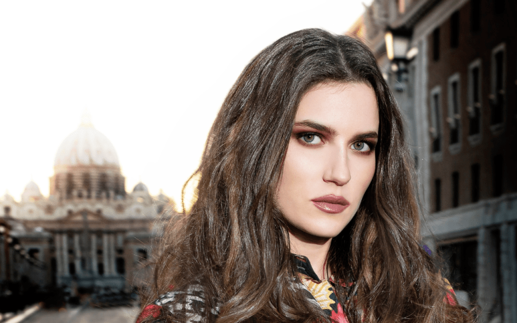 Primo piano di una modella con una vestito colorato, è in posa e mostra una acconciatura con le extension di Luxury Wigs.